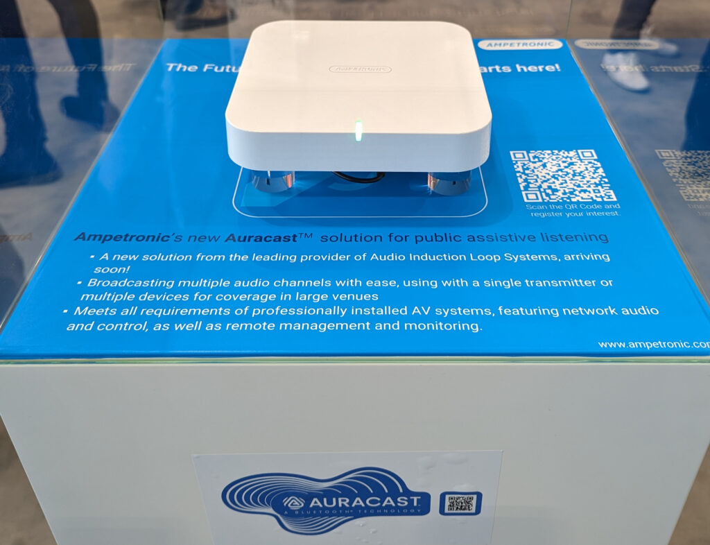 Eine Vitrine mit einem handteller-großen weissen Plastik-Gerät - ein Sender für Auracast Bluetooth