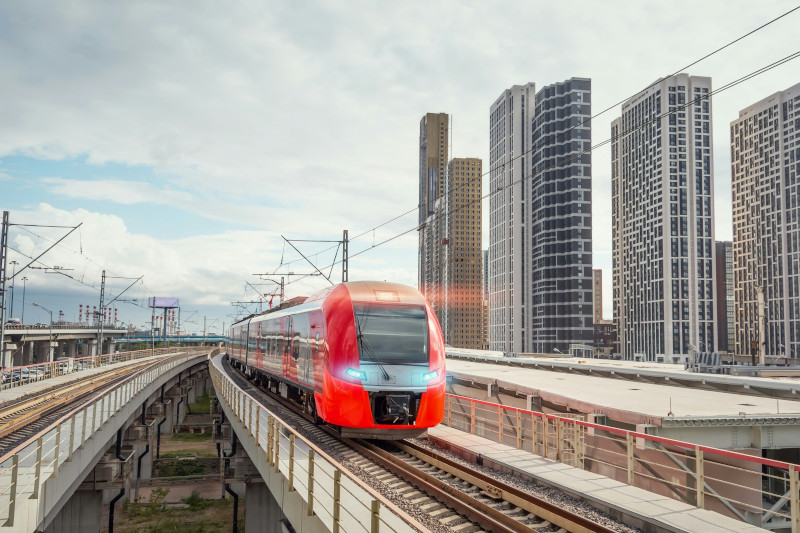 Ein roter Schnellzug vor eine modernen Stadtsilhouette