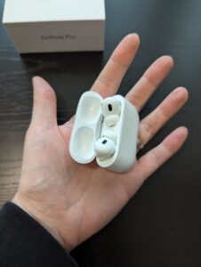 Die Airpods in ihrer Ladeschale in meiner Hand.