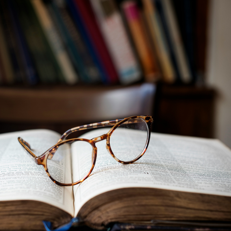 Eine Lesebrille auf einem aufgeschlagenen Buch liegend